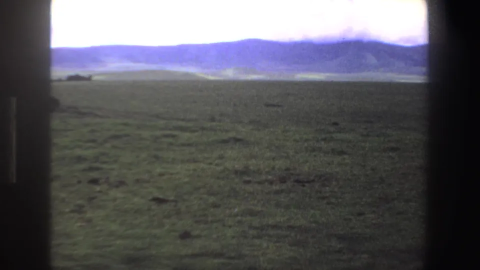1969 South Africa home-movie frame of open green grassland and distant hills after the picnic subjects leave view.