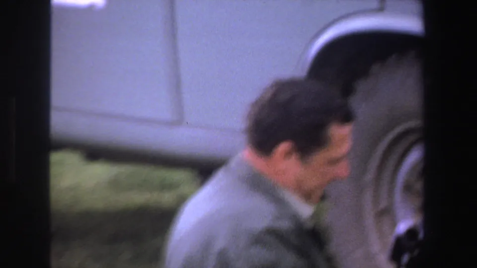 A man in a light-colored jacket appears beside an off-road vehicle in 1969 South Africa home-movie footage.