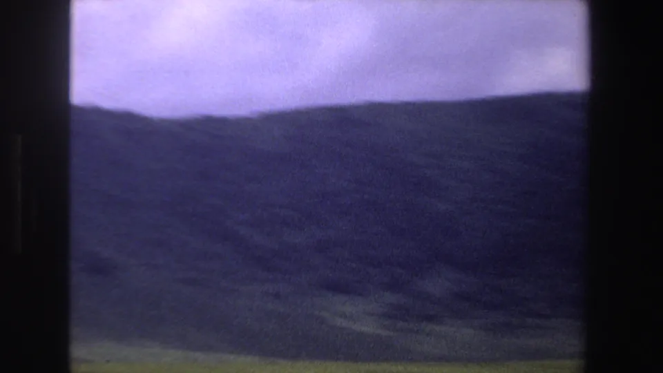 A dark ridgeline and green hillside fill the frame in purple-tinted 1969 South Africa 8mm footage.