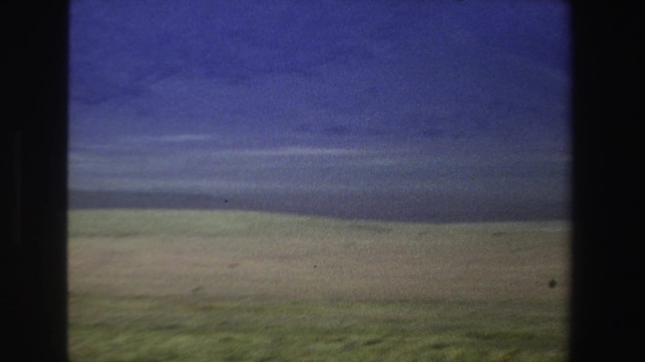 Muted plain and distant ridge line under layered blue-gray clouds.