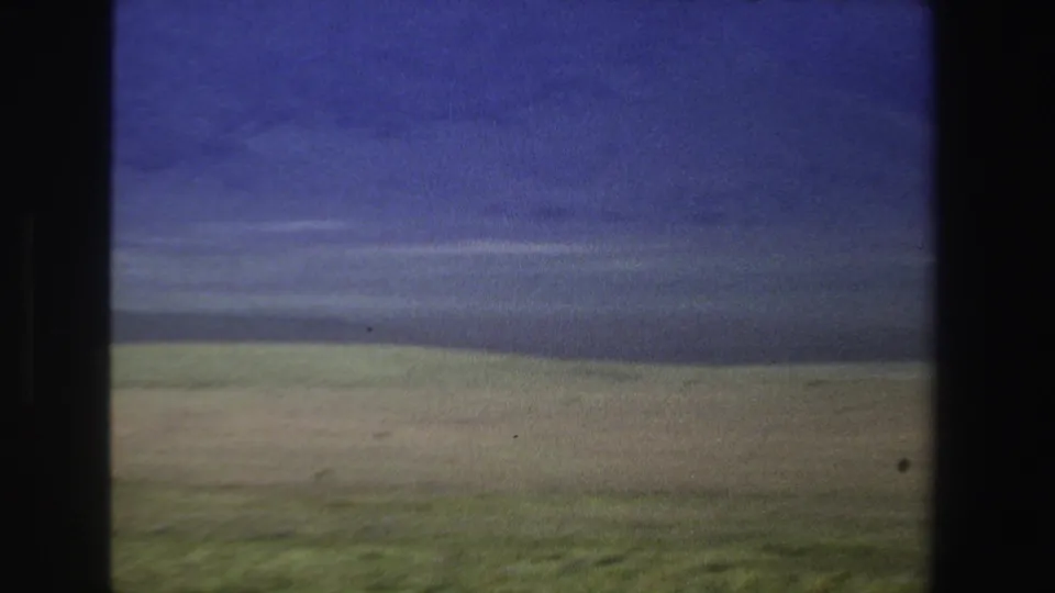 1969 South Africa 8mm view of open countryside with a low horizon and layered blue-gray storm clouds.