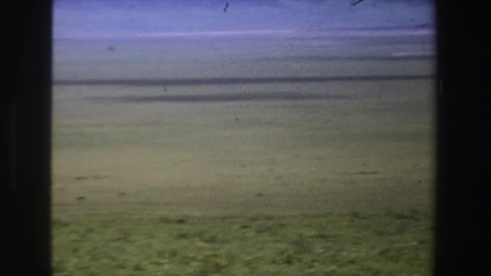 1969 South Africa 8mm frame showing open grassland and distant plain, partly blocked by dark gate edges.