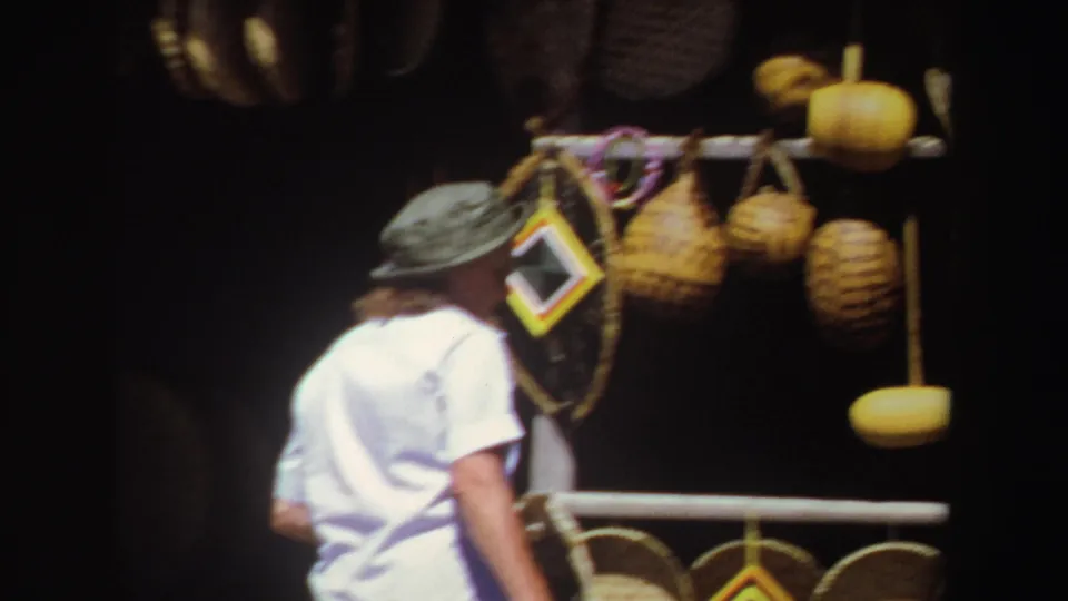 A close 1969 South Africa market view shows the visitor near colorful framed pieces, baskets and hanging gourds.