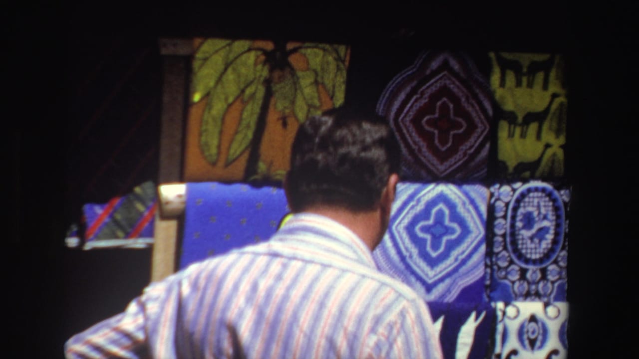 Man seen from behind while looking at patterned scarves and shawls on racks.