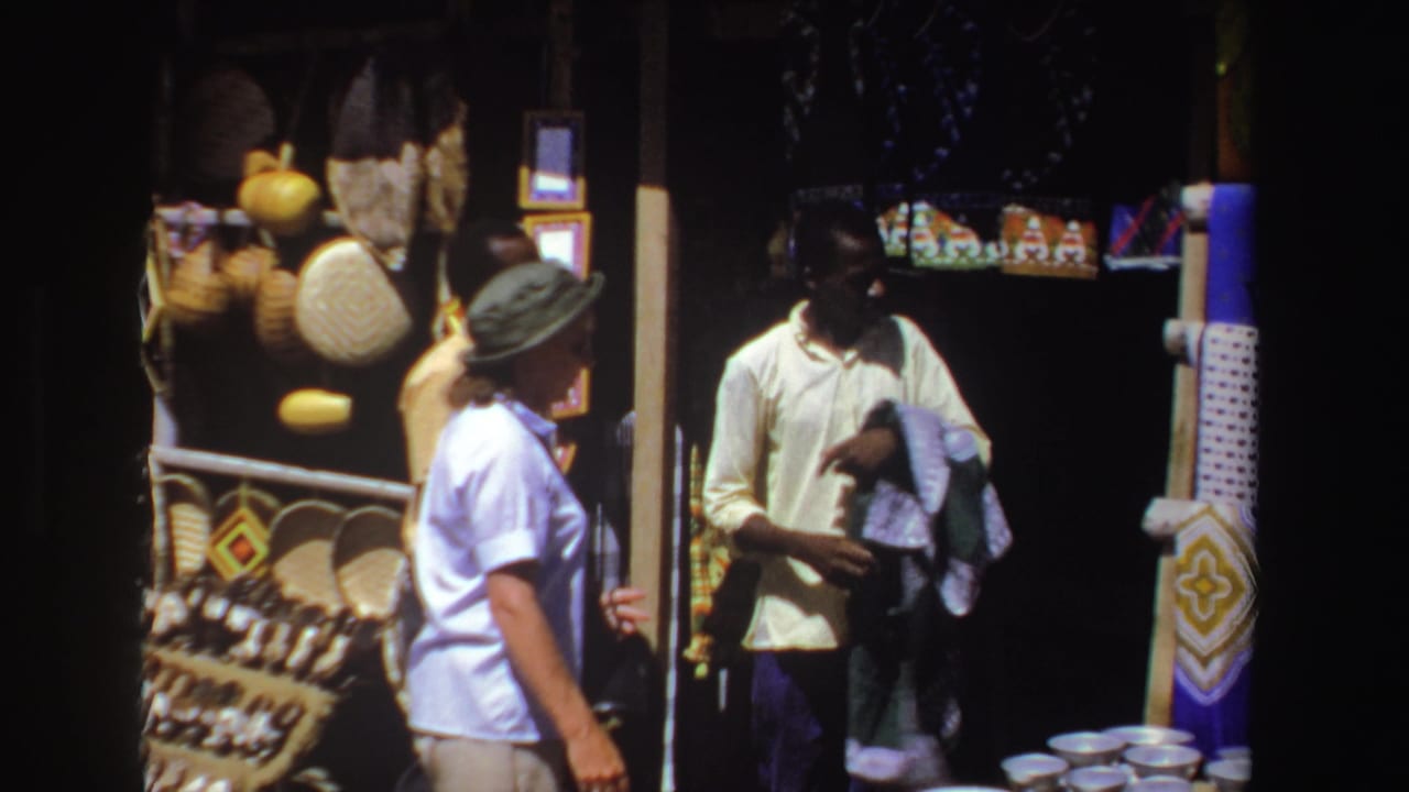 Merchant holds folded textiles while a woman faces him at the stall.