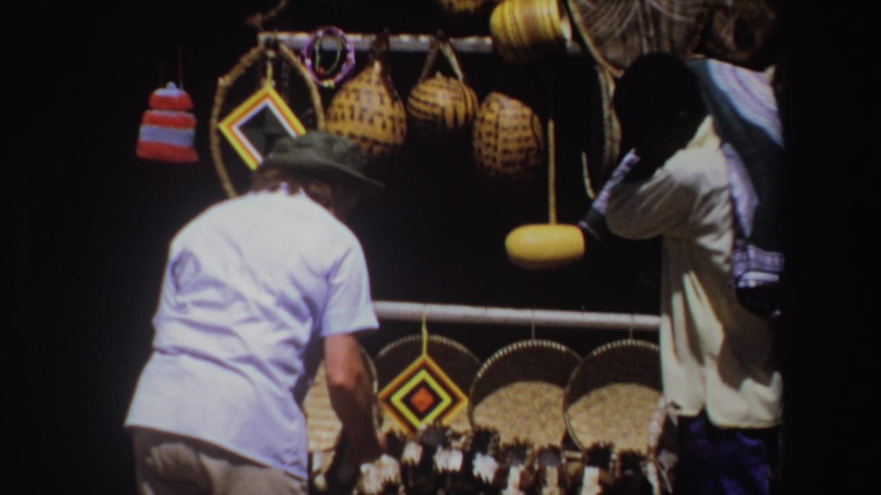 Two adult men browse a market stall with woven baskets and hanging crafts.