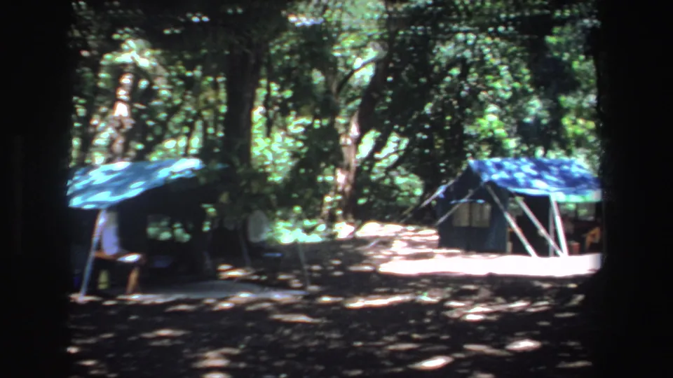 Home-movie frame from South Africa, 1969, showing tents and camp equipment in wooded shade.