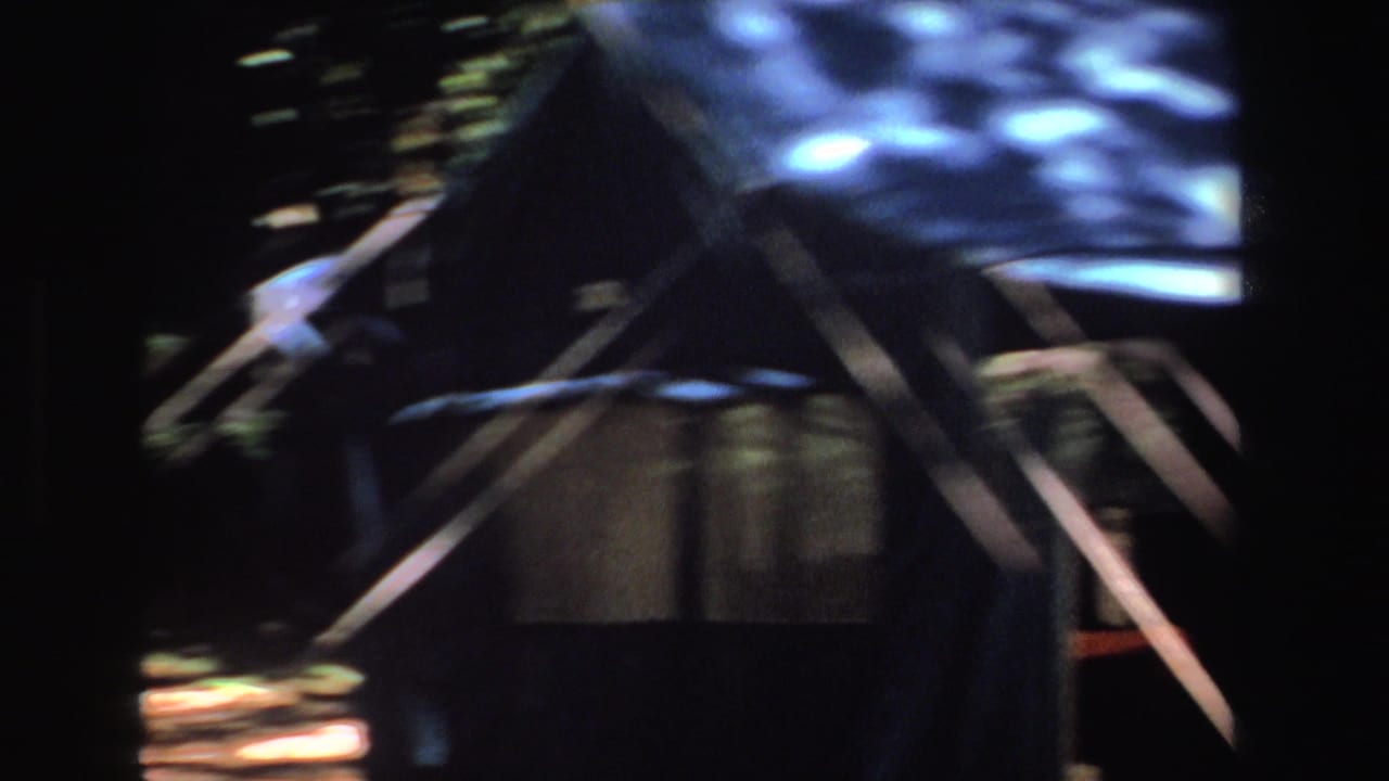 Blurred view of tent roof, support poles, and shaded campsite structure.