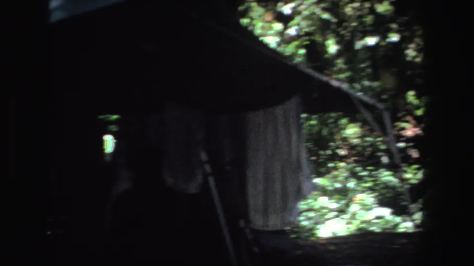 Dim 1969 South Africa campsite frame with hanging tent fabric and bright foliage outside.