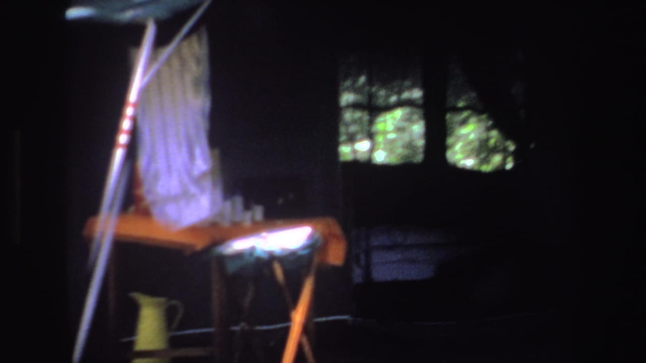 Shaded tent interior or campsite area with cloth, poles, a table, and a yellow jug.