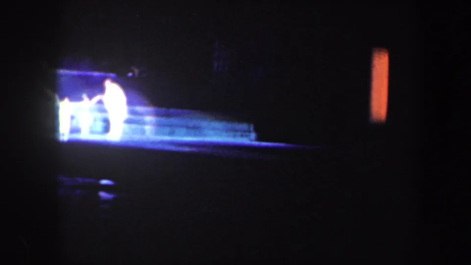 Baltimore 1960 stage footage shows bright figures or props near steps, with most of the theater space falling into shadow.