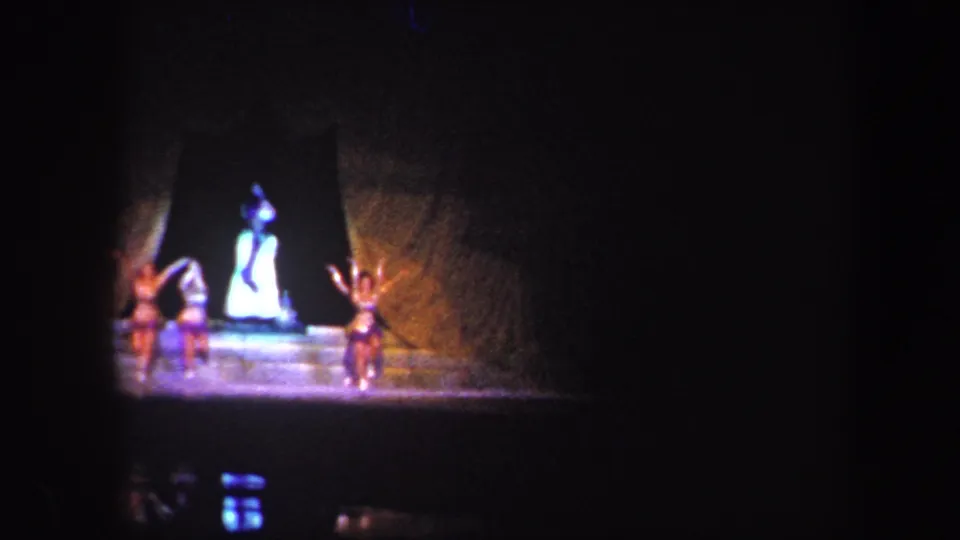 1960 Baltimore stage performance with a bright central dancer and surrounding figures under warm and blue theatrical light.