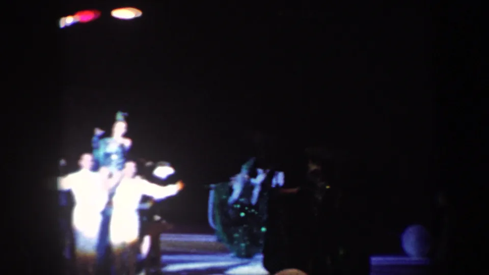 Baltimore 1960 8mm frame showing a distant circus-style group routine with performers in white and dark costumes.