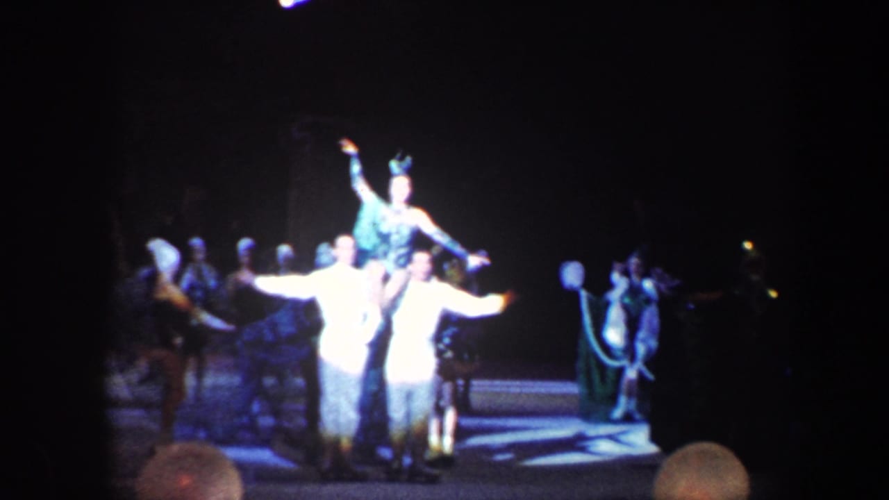 An acrobat is lifted above two performers while other circus figures stand nearby.