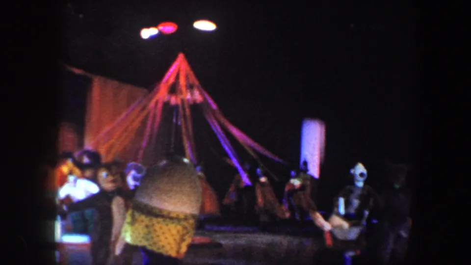 A later view of the circus stage shows performers beside a tent-like prop, partly obscured by an audience member in the foreground.