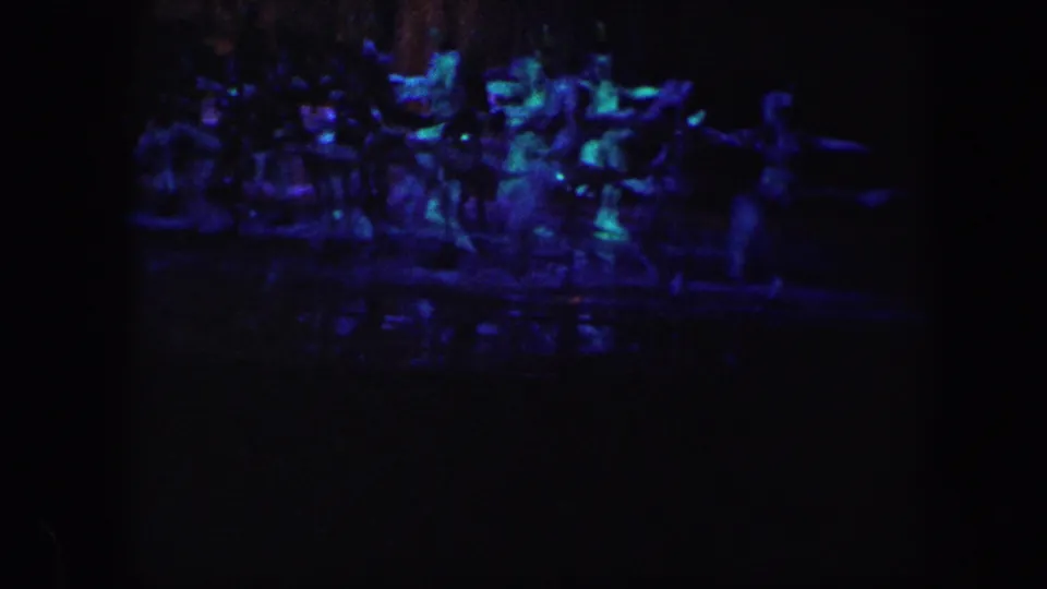 A distant group of ice-show performers appears under blue and purple stage lighting in the 1960 Baltimore 8mm footage.