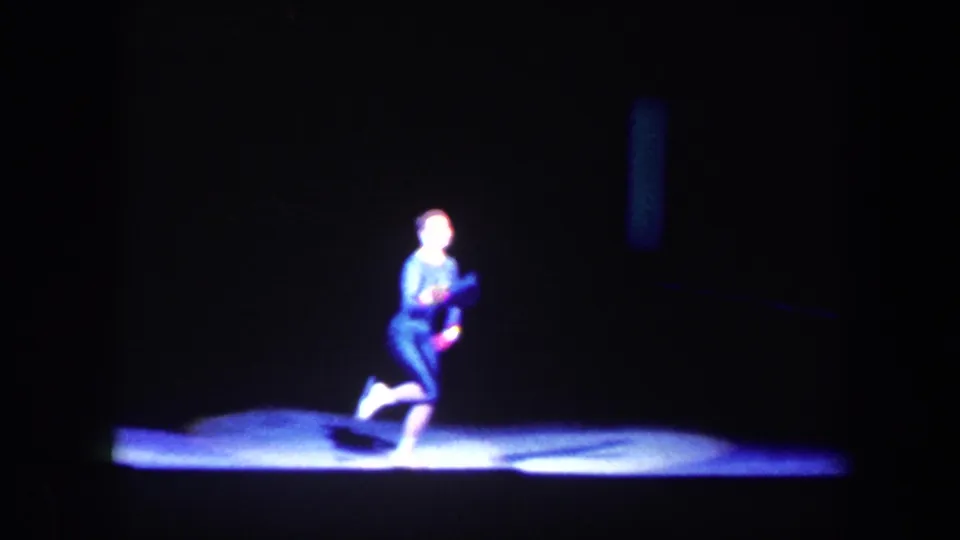 1960 Baltimore 8mm frame with a solo performer in a dark outfit posing low in a bright stage spotlight.