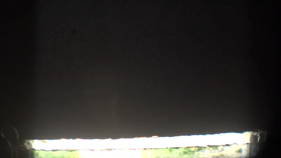 Mostly dark 8mm frame with a bright horizontal exposure band and little identifiable scene detail visible.