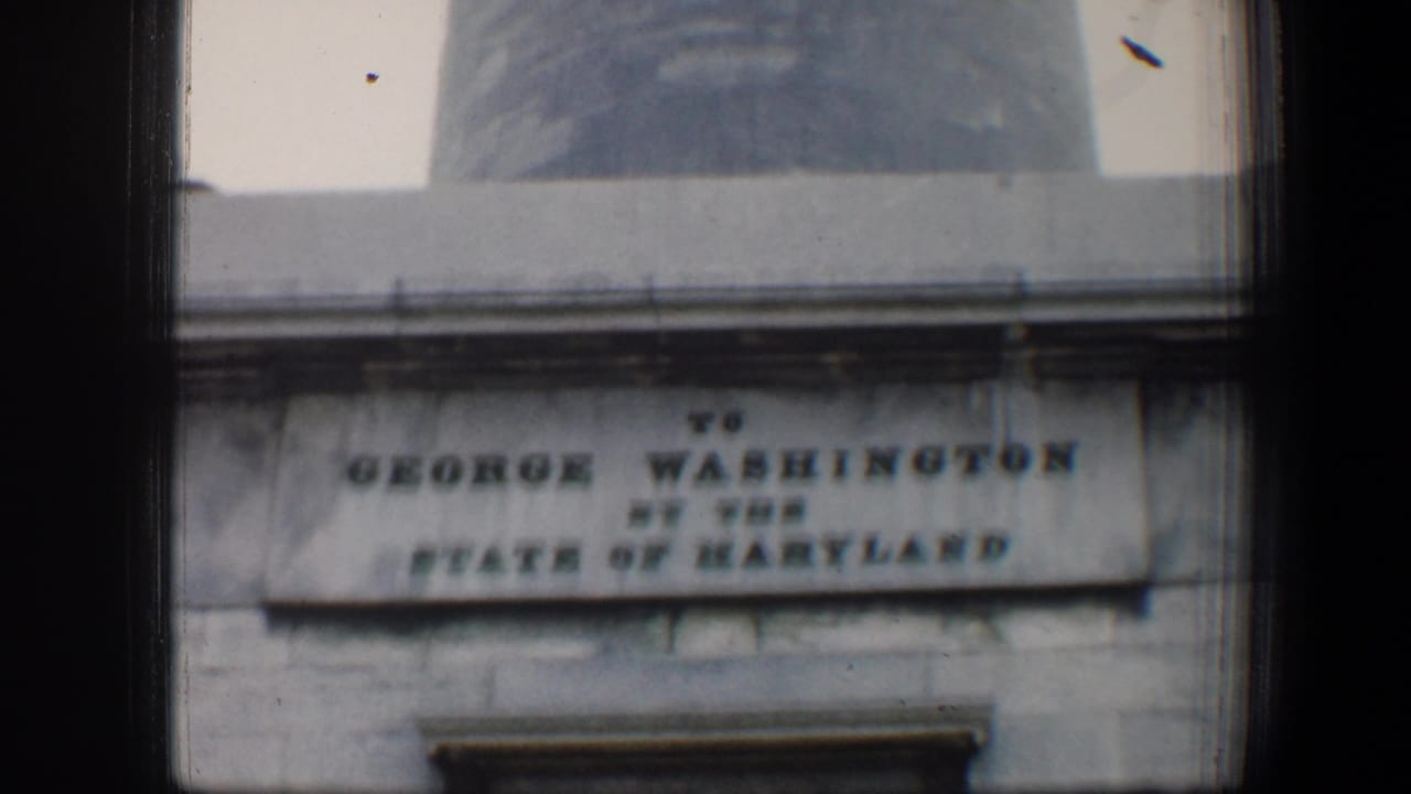 Stone inscription panel below a tall monument shaft, framed by dark 8mm film edges.