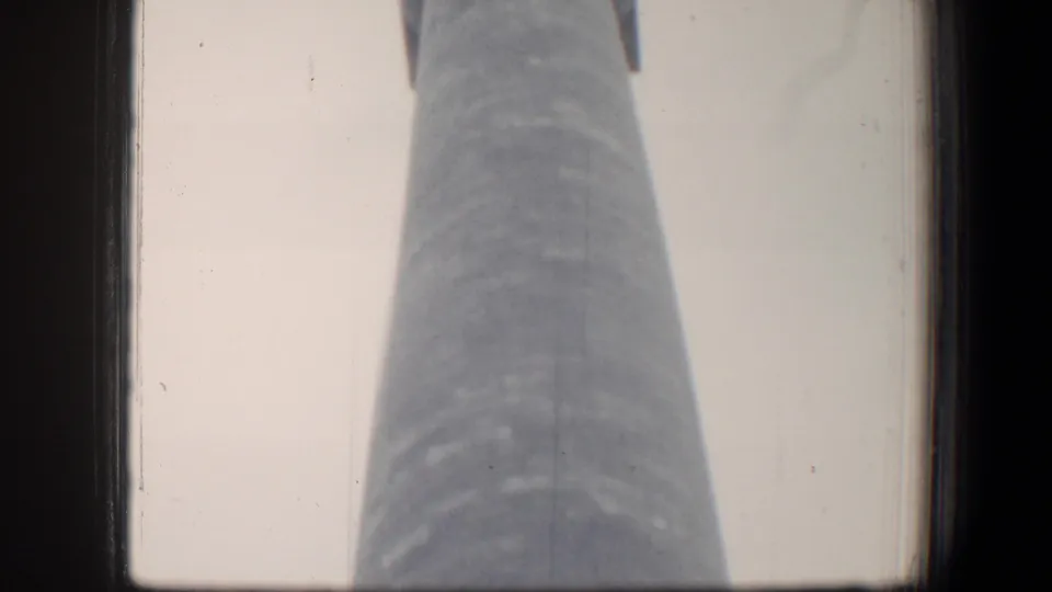1960 Baltimore frame showing a tall civic monument from below, with visible 8mm gate edges and grain.