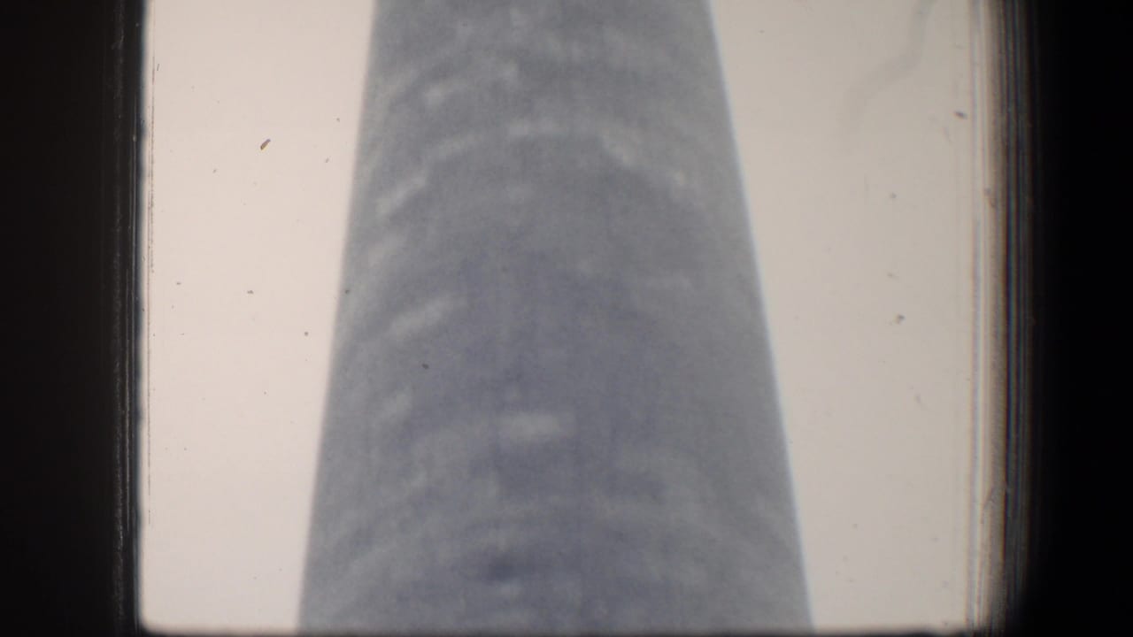 1960 Baltimore 8mm frame showing a low-angle view of the George Washington Monument shaft under overcast light.