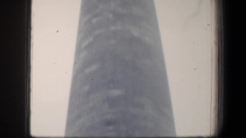 1960 Baltimore 8mm frame showing a low-angle view of the George Washington Monument shaft under overcast light.