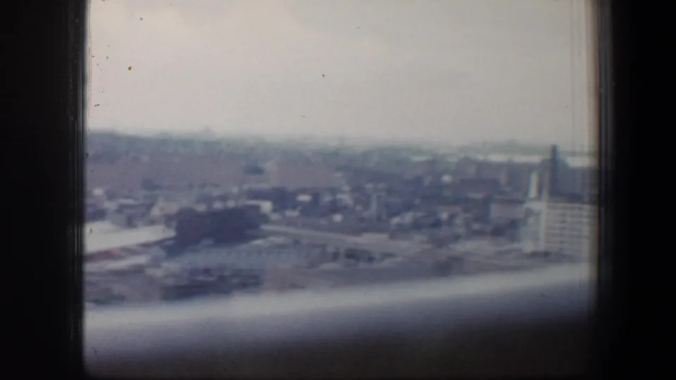 Baltimore urban view in 1960, with distant buildings, a vertical tower-like structure, and dark interior framing across the image.