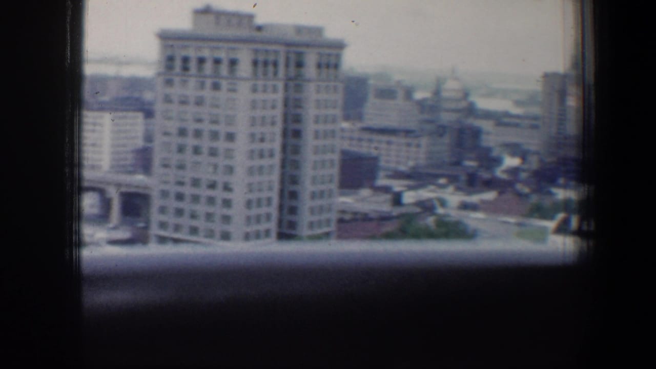 1960 Baltimore downtown buildings seen from an elevated window-framed viewpoint on 8mm film.