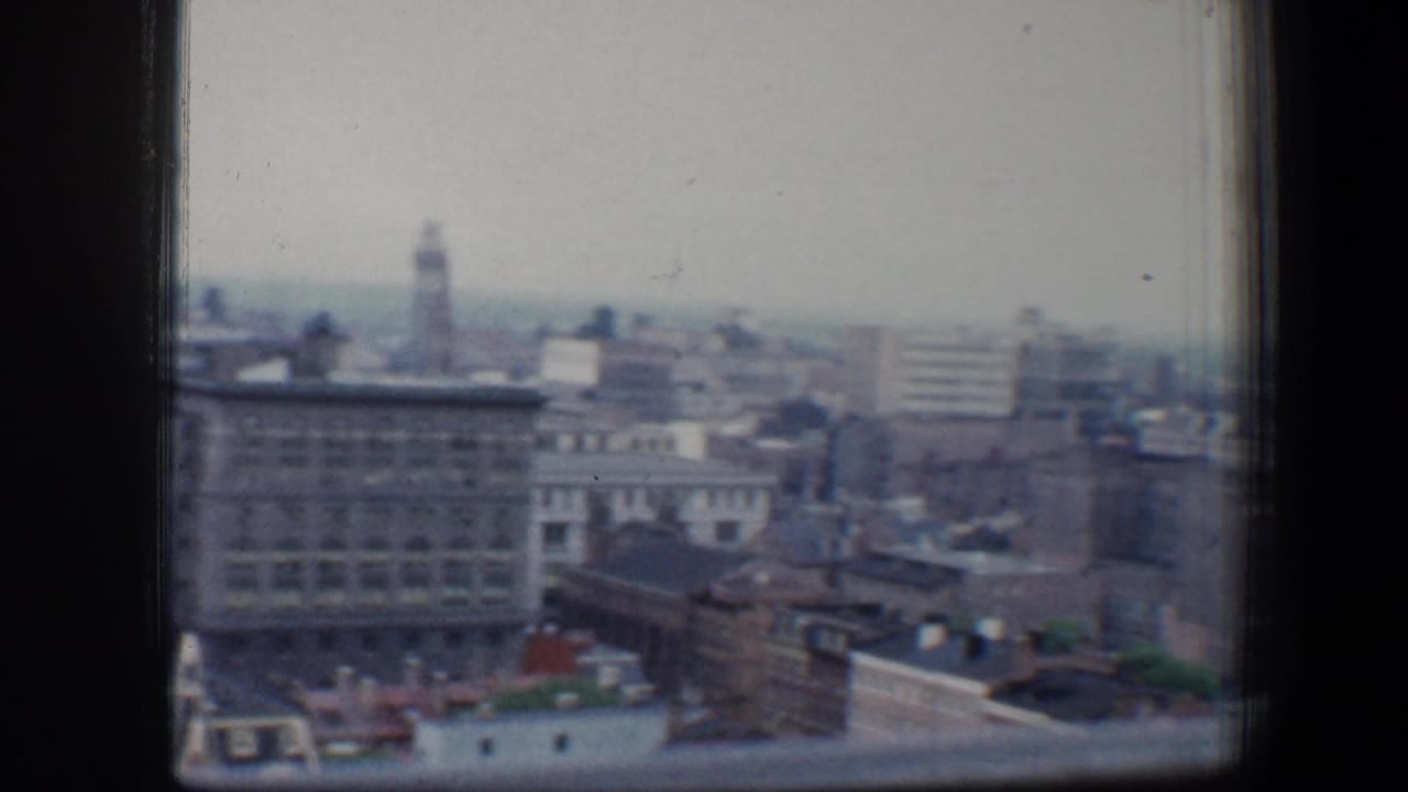 Baltimore city buildings seen through a dark window frame from a high vantage.