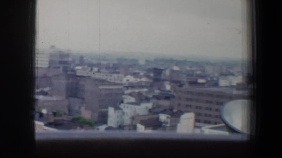Baltimore skyline and rooftop blocks appear beyond the upper right window pane in soft 8mm color.