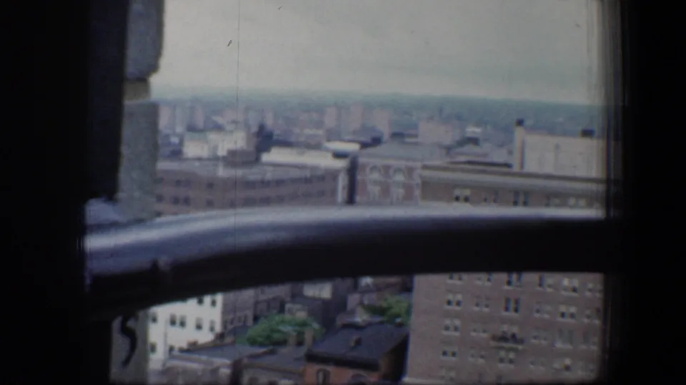 Lower left window view over Baltimore rooftops, brick buildings, and a distant urban horizon.