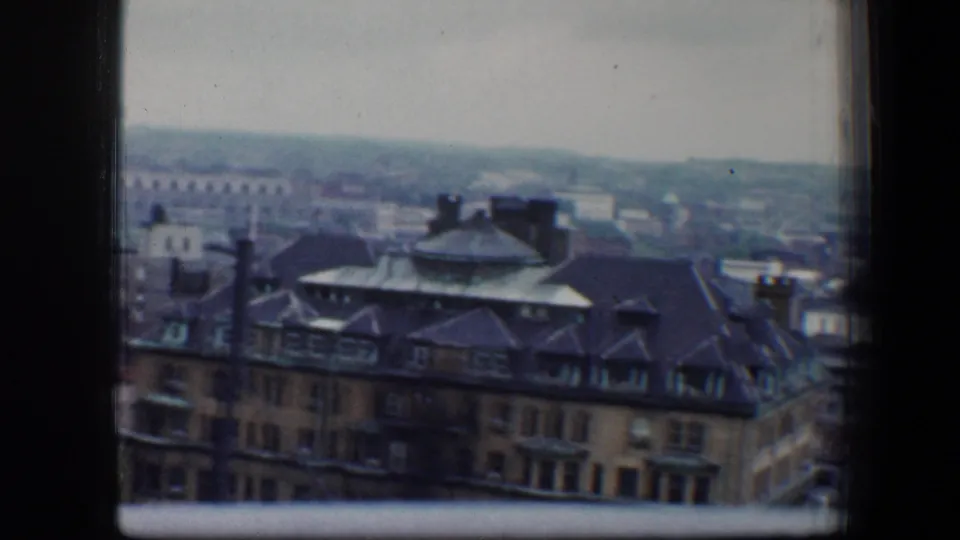 1960 Baltimore high-rise view centered on a large older roofed building, with dense blocks and a hazy horizon beyond.