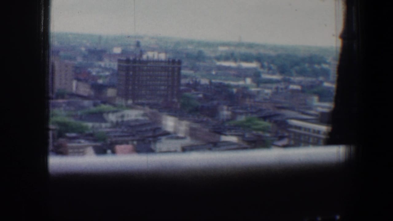 1960 Baltimore city view from a high vantage point, with soft distant buildings and dark window framing in the foreground.