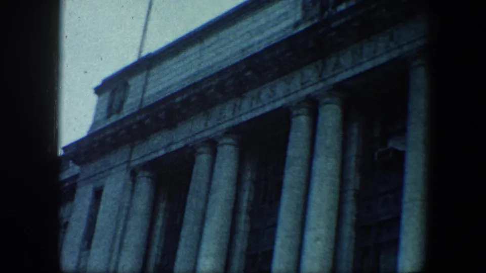 Angled 1960 Baltimore view of a large columned facade, with dark vertical framing and pale sky at the edge.