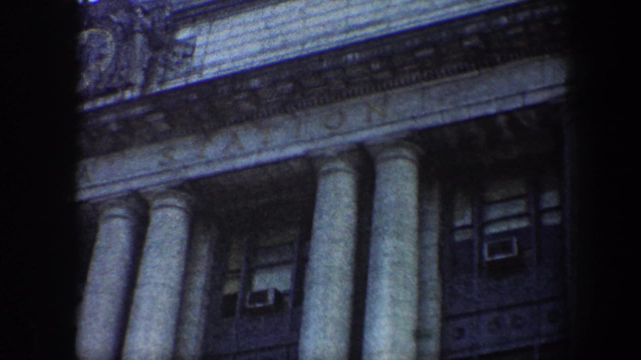 1960 Baltimore 8mm frame showing a low-angle view of tall stone columns, upper windows, and carved masonry on a grand facade.