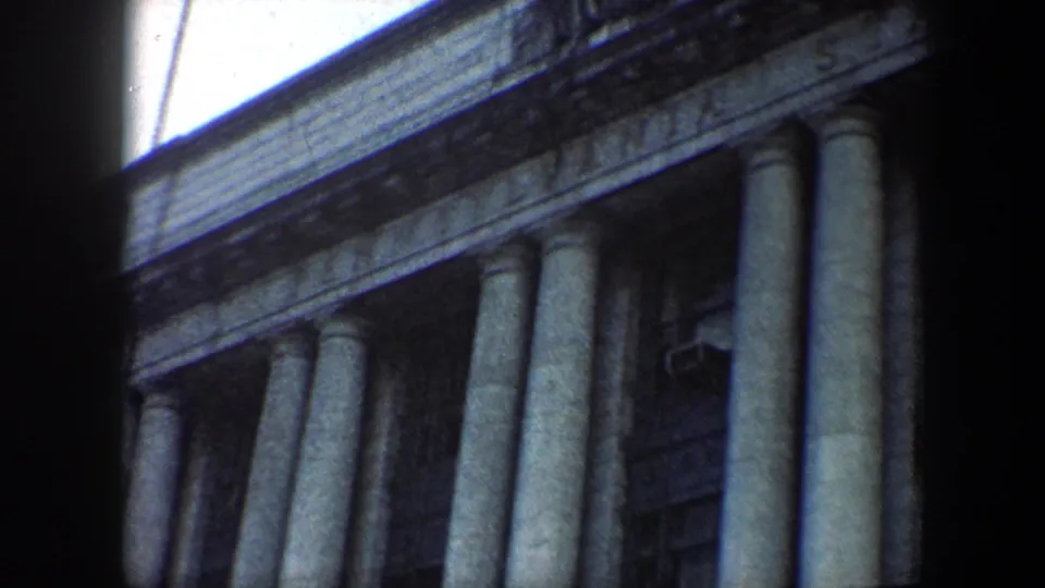 1960 Baltimore 8mm frame of a classical-style building facade with columns, carved trim, and a window air conditioner.