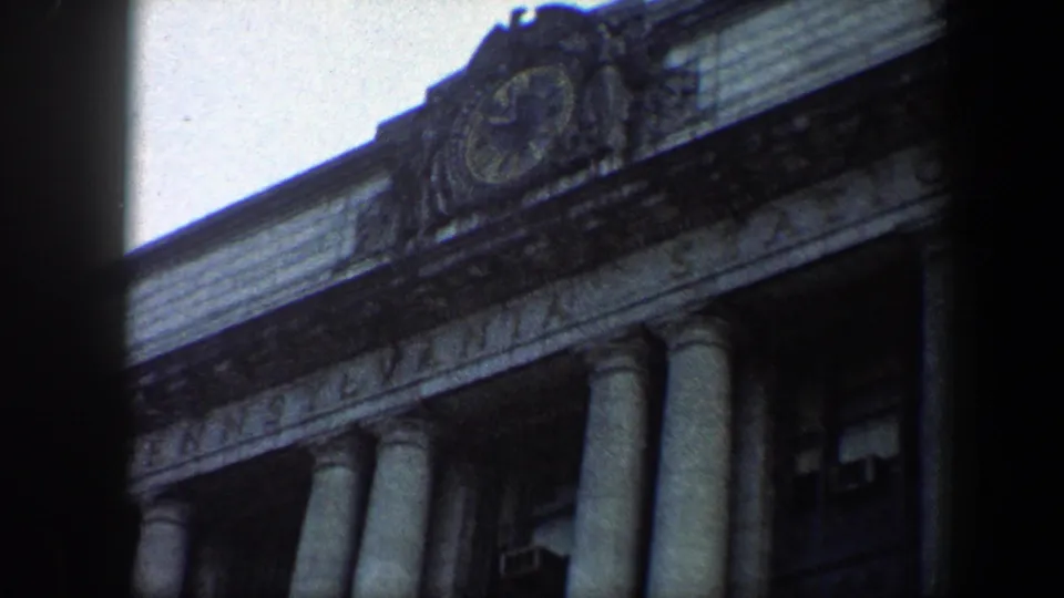 1960 Baltimore 8mm frame showing a round clock ornament, partial station lettering, and tall columns on a monumental facade.