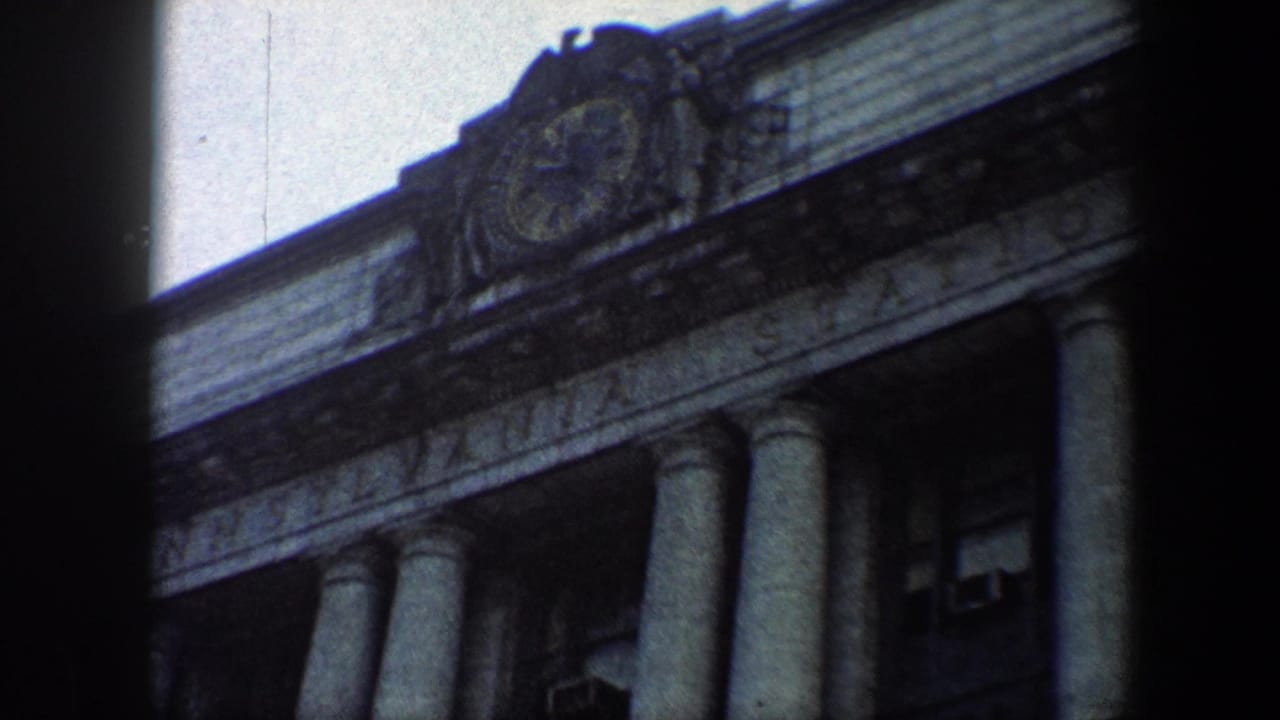 Upper facade of a columned station building with a round clock near the roofline.