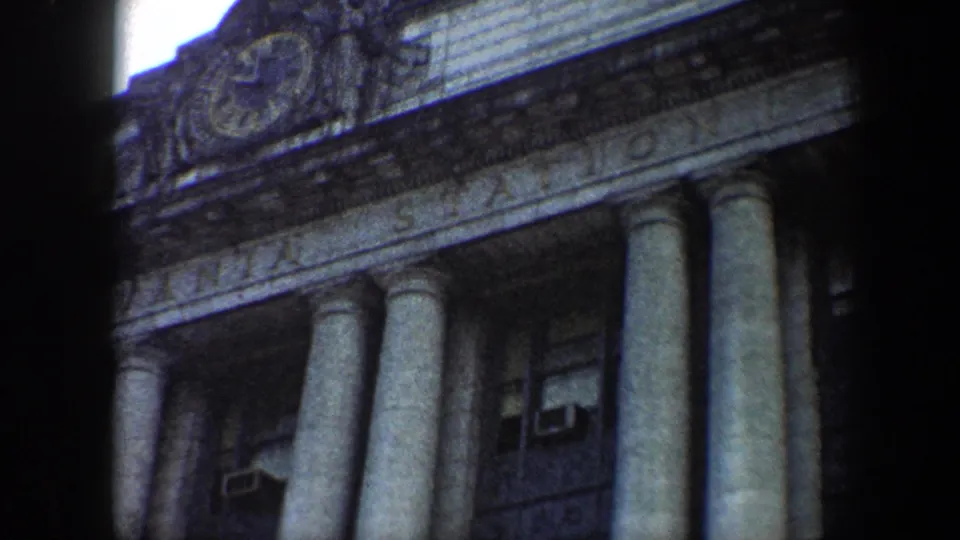 Baltimore station exterior in 1960, framed through dark film edges with the clock, columns, and upper windows visible.