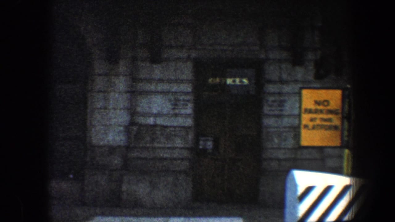 Stone building doorway beside a yellow no-parking sign and striped barrier.
