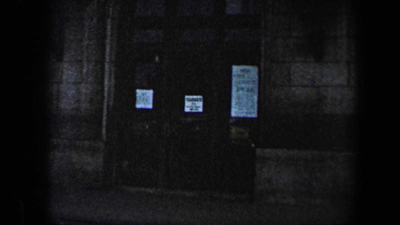 Shadowed doorway with paper signs and a posted notice on the right door.