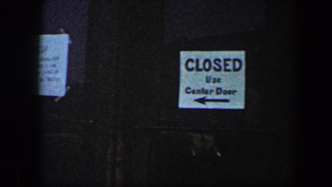1960 Baltimore frame showing a dark exterior surface with a printed “CLOSED Use Center Door” sign and arrow.