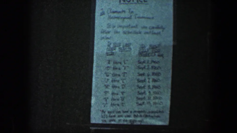 1960 Baltimore frame showing a handwritten unemployment insurance schedule with September dates posted on a dark exterior surface.