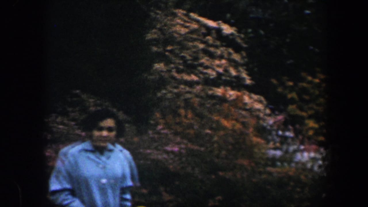Woman in a blue shirt walking through a shaded flower garden.
