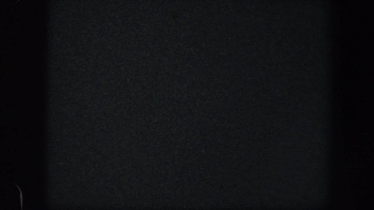 Mostly dark frame with faint film edge and grain.