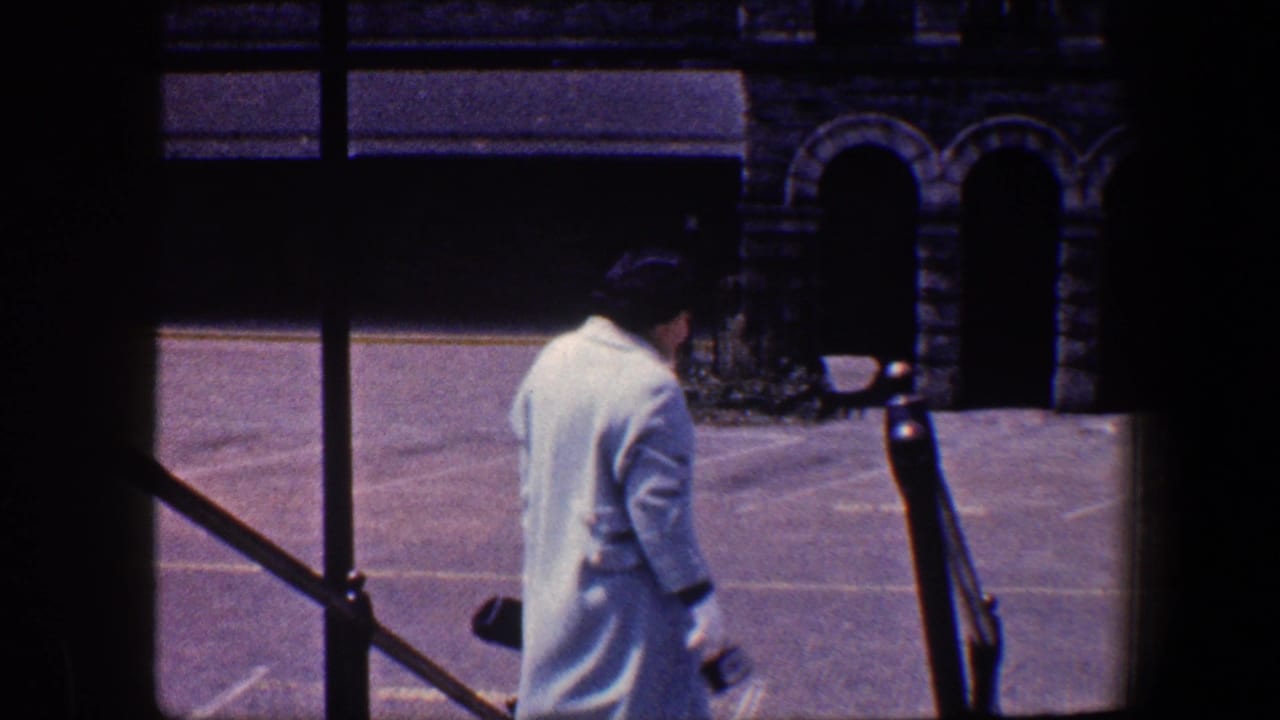 Woman in a light blue coat walks down exterior steps beside railings and arched stone doorways.
