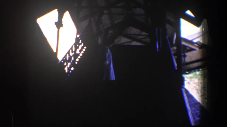 Late frame from a 1960 Baltimore 8mm interior showing bright side light, a stair railing, and blue-tinted shadow detail.