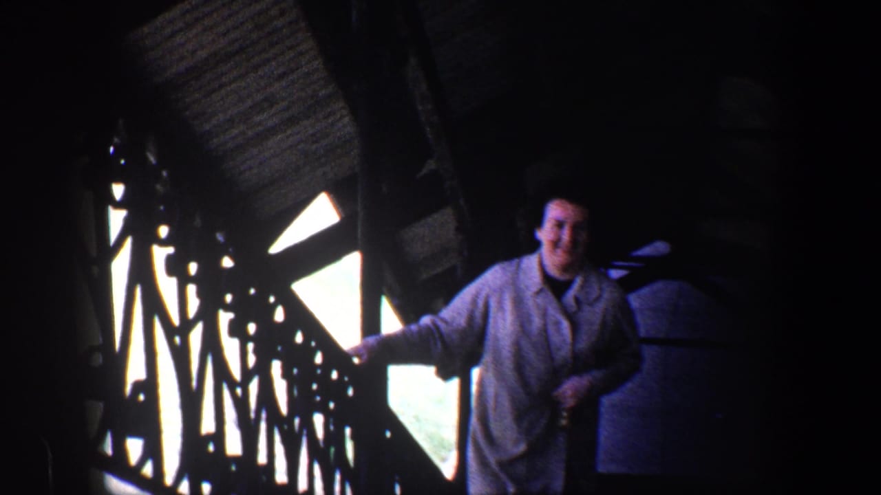 Woman smiling beside metal railings in a dim interior structure.