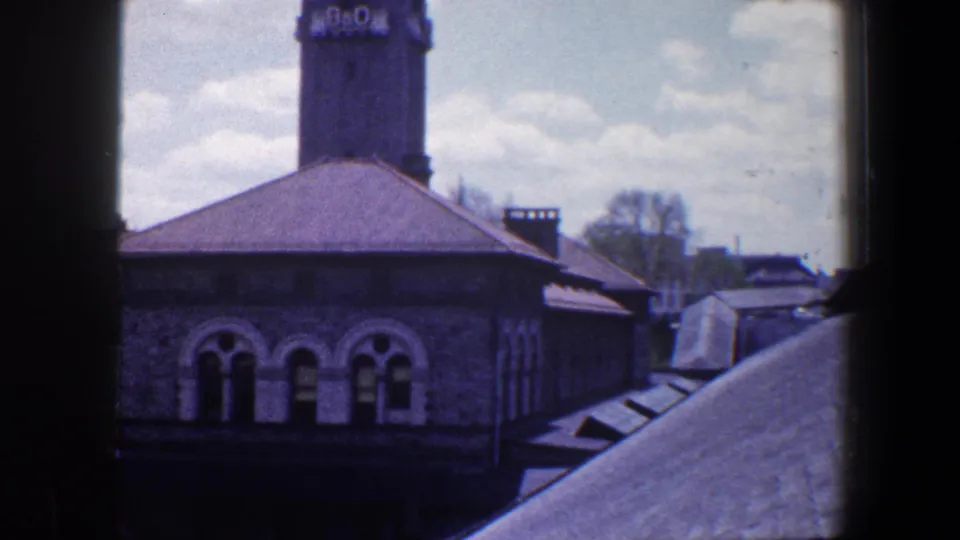 1960 Baltimore 8mm frame emphasizing arched windows, stonework, roof surfaces, and the lower portion of the B&O tower.