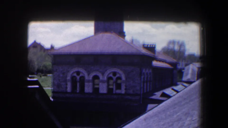 Final 1960 Baltimore home-movie frame showing the stone facade, arched windows, roofline, and cropped B&O clocktower.